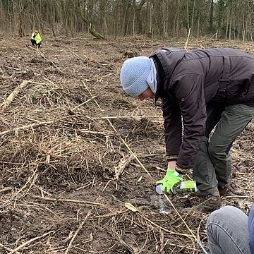 Eine Person bückt sich markiert eine Brache.