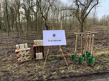 Berief Plakat auf einem Aufsteller vor einem Wald mit Berief Getränkekartons im Hintergrund.