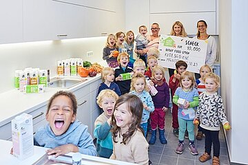Kinder des Kindergartens lachen in die Kamera, halten ein Plakat von Berief hoch, daneben Getränkekartons von Berief.