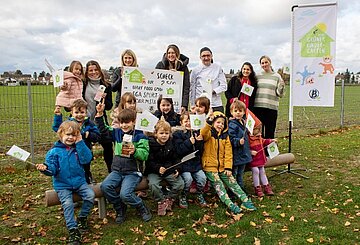 Kinder auf einer Wiese, die ein Plakat von Berief hochhalten.