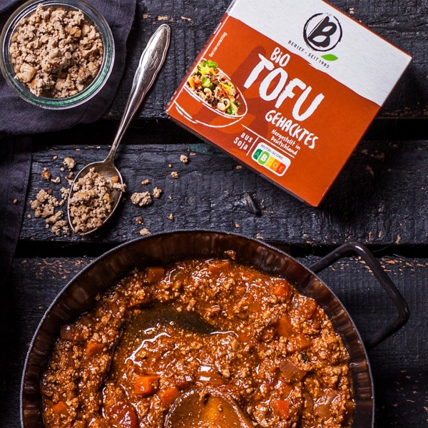 Gußeiserne schwarze Pfanne mit Bio-Tofu-Gehacktes, daneben die Packung des Gehackten