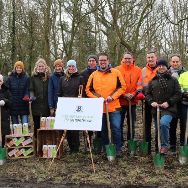 Menschen stehen in warmer Kleidung mit Spaten auf einer Wiese.