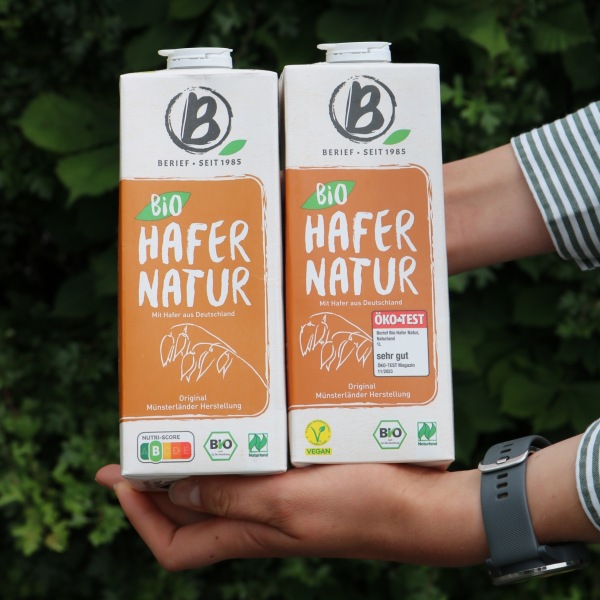 Jemand hält zwei Hafergetränkekartons in den Händen.