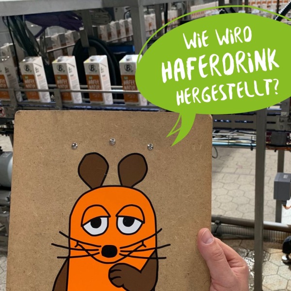 Ein Bild von "Die Maus" wird in die Kamera gehalten mit der Frage: wie wird Hafermilch hergestellt?