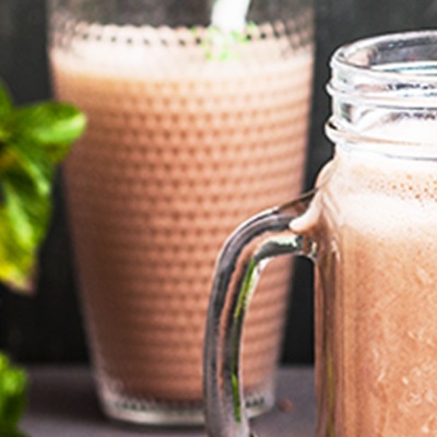 Schokofarmbenes Shake in zwei Gläsern mit Trinkhalm