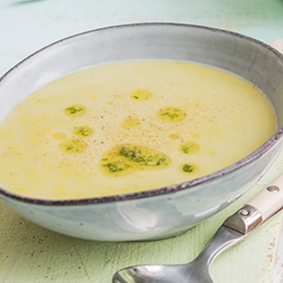 Cremfarbige Suppe in einer hellen Tonschale garniert mit Kräutern