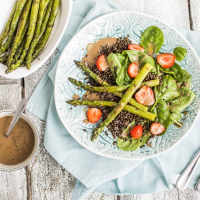 Spargel und Erdbeeren auf Blattsalat und Linsen mit Dip Dip auf einem Tisch.