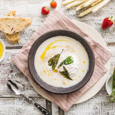 Cremfarbige Suppe mit Chips auf einem Tischtuch und Dekoration.