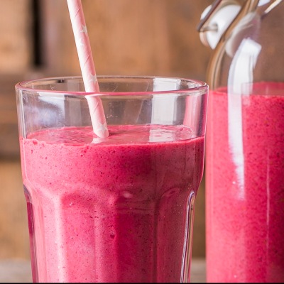 Hellrotes Smoothie in einem Glas mit Strohhalm