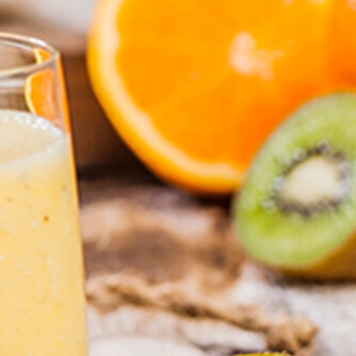 Helles Getränk im Glas mit Früchtedekoration